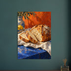Sliced crusty loaf on cream cloth over a blue table, with lemons, pottery and olive branches against an orange backdrop.