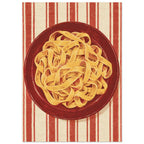 Golden pasta ribbons on a deep red plate, viewed from above against textured red and cream vertical stripes.