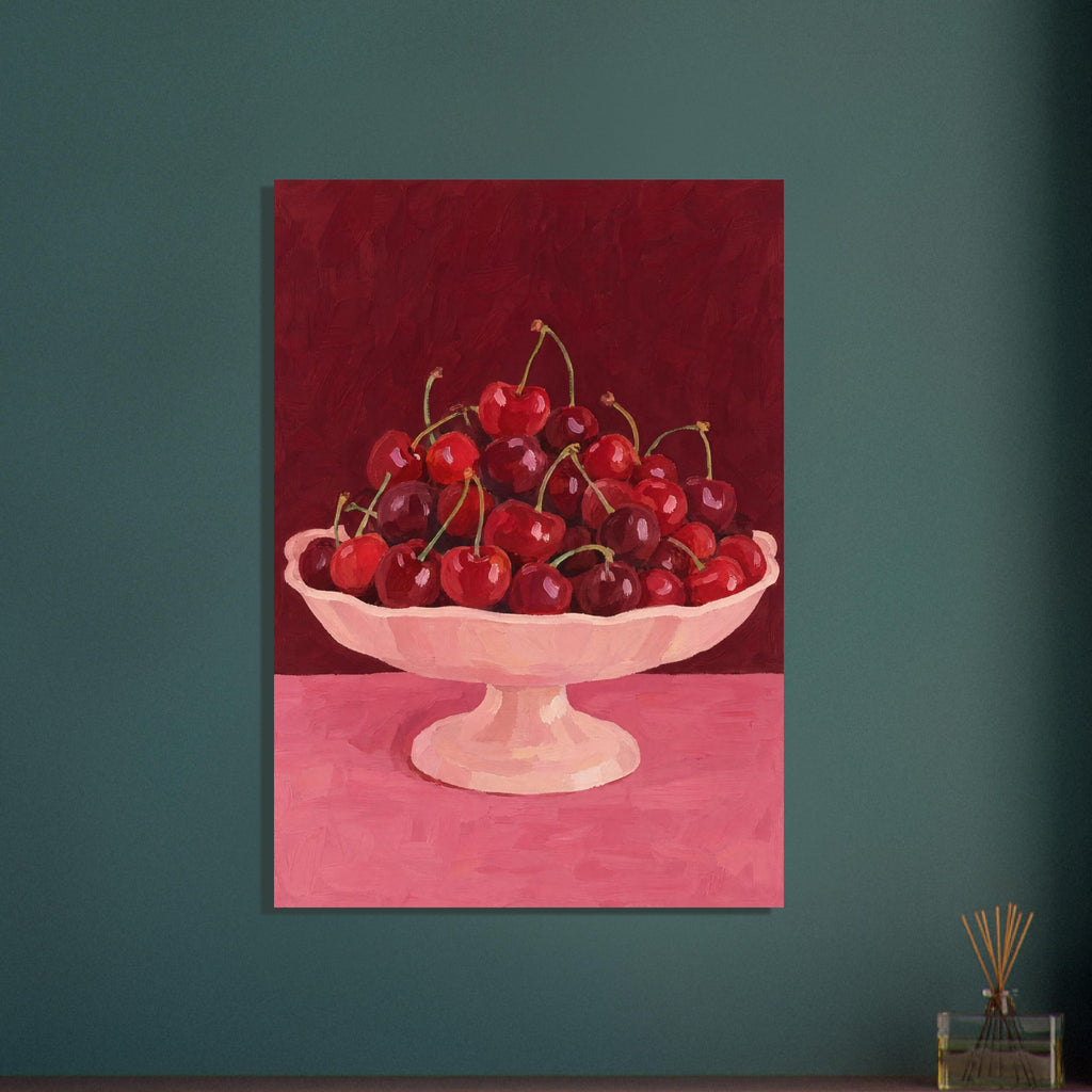 Red and burgundy cherries in a pale pink pedestal bowl on a pink tabletop against a deep red painted background.