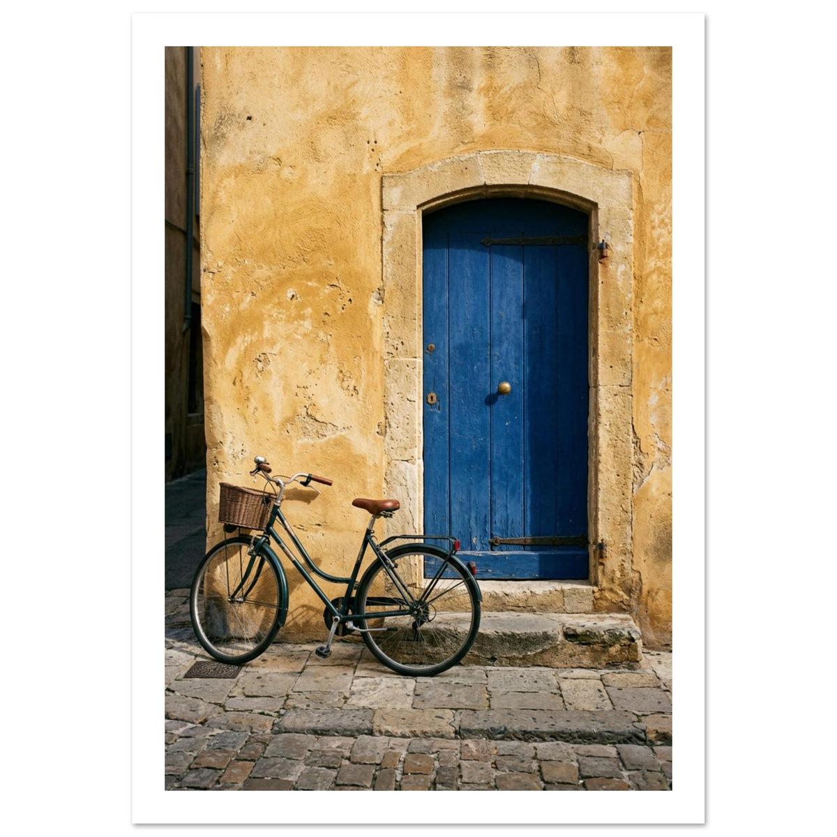Green bicycle with a woven basket beside a blue wooden door in a golden plaster wall, above worn stone paving.