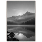 Mountain peaks and conifer forests reflected in a misty lake, with rocks in the foreground, in black and white.