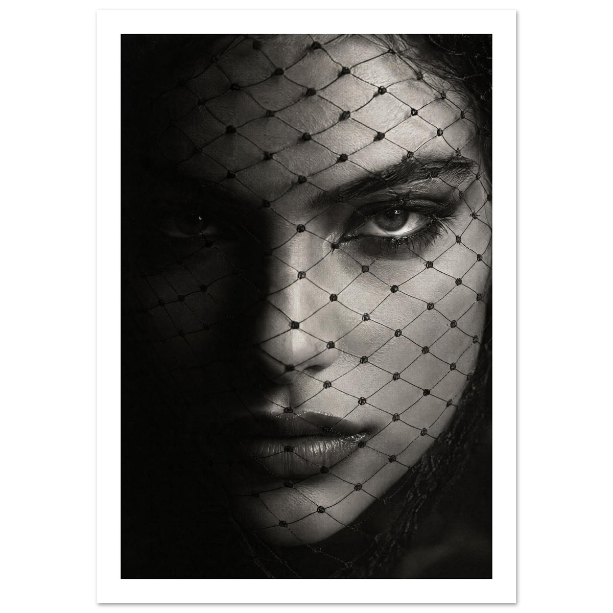 Woman's face behind a diamond-patterned net veil, with one eye brightly lit and the other in deep shadow, in black and white.