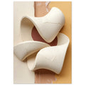 Cream ribbon-like sculptural curves with cracked surfaces against vertical areas of cream, peach and muted yellow.