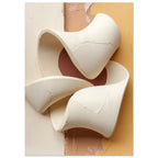 Cream ribbon-like sculptural curves with cracked surfaces against vertical areas of cream, peach and muted yellow.