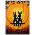 Two black rabbits with white tails hold paws on a swing, surrounded by branches and grass against yellow and orange swirls.