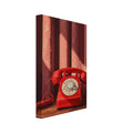 Red rotary telephone with a cream dial and coiled cord on a wooden table before burgundy curtains crossed by sunlight.
