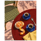Two blue coffee cups, a peeled orange, spoon and yellow cloth on a red table beside a green woven chair and pink tiles.