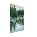 Watercolour pine forest beside a lake, with green trees reflected in blue-grey water beneath a cloudy sky.