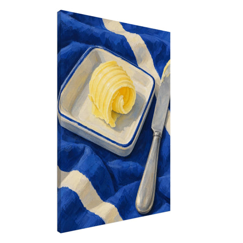 Butter curl in a cream dish with a blue rim, beside a silver-coloured knife on blue and cream striped fabric.