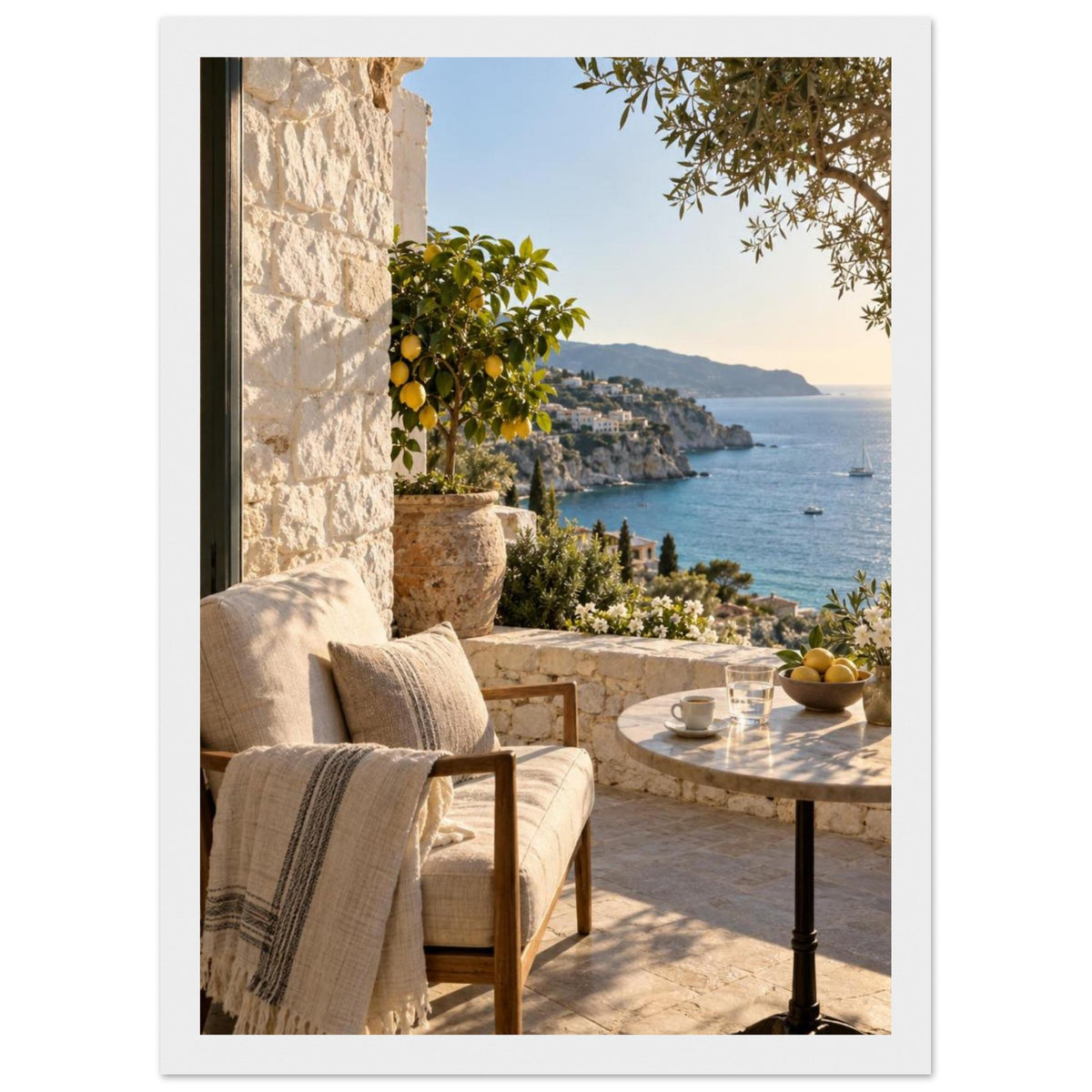 Lemon tree on a stone terrace with a cushioned chair, round table and blue sea overlooking a rocky coastline.