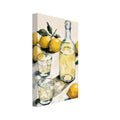 Yellow lemons with green leaves surround a glass bottle and two ice-filled tumblers on a cream tabletop.
