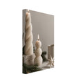 Two lit cream sculptural candles beside a ceramic mug, folded paper star and evergreen branches on beige fabric.
