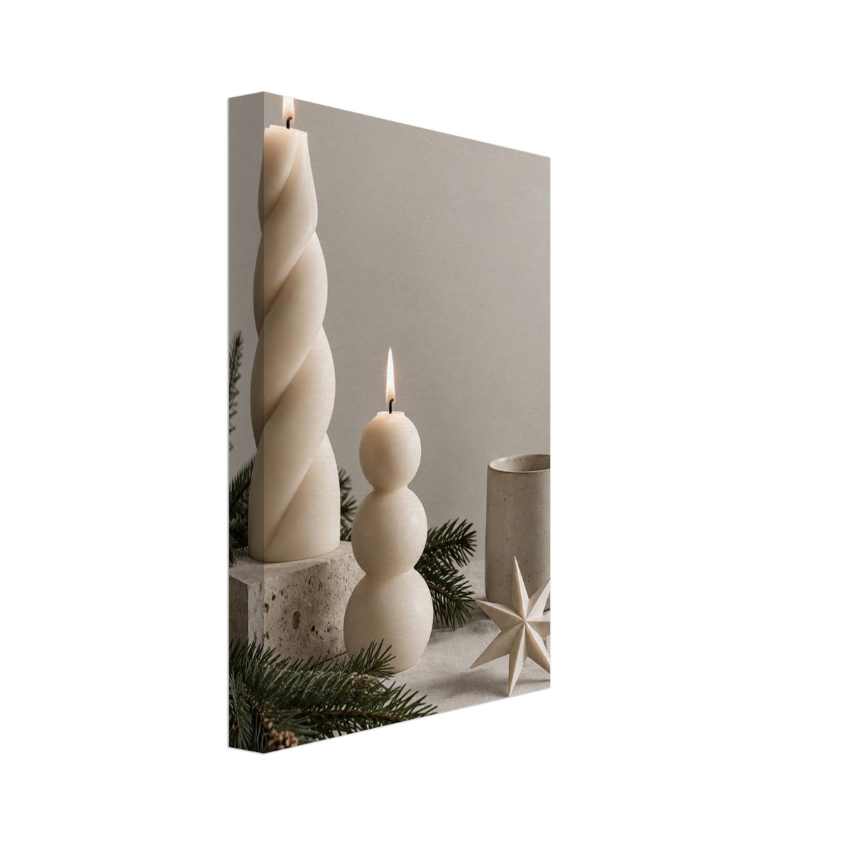 Two lit cream sculptural candles beside a ceramic mug, folded paper star and evergreen branches on beige fabric.