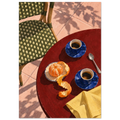 Two blue coffee cups, a peeled orange, spoon and yellow cloth on a red table beside a green woven chair and pink tiles.