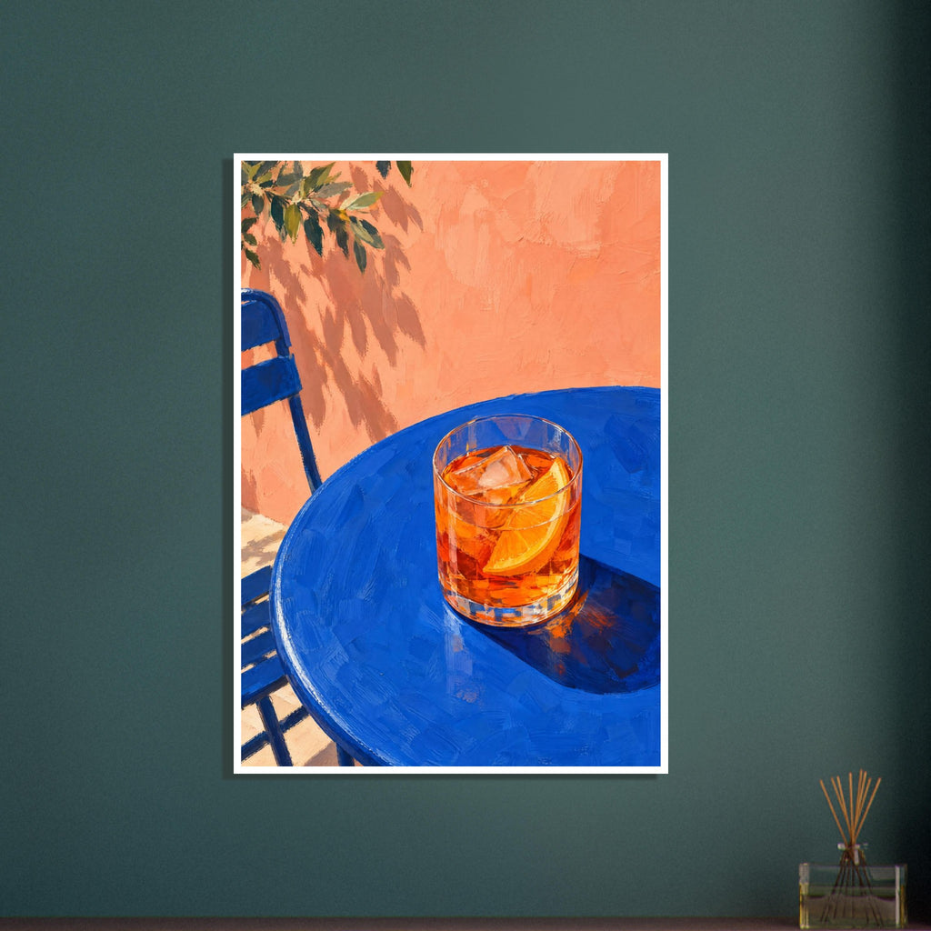 Orange cocktail with ice and an orange slice on a blue table, beside a blue chair and peach wall with leafy shadows.