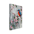 Blue and orange kingfisher perched among pink blossoms and green leaves against a grey background with paint drips.