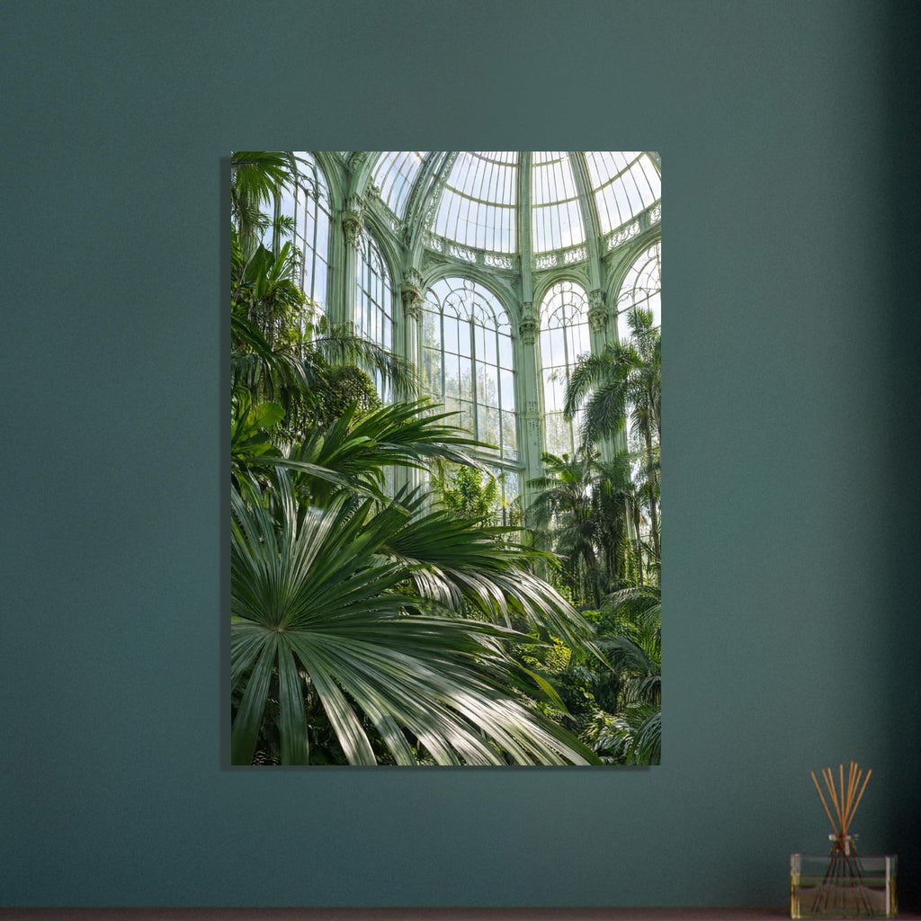 Lush palm fronds beneath tall arched windows and an ornate, pale green metal and glass roof in a sunlit glasshouse.