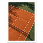 Terracotta tennis court viewed from above, with green surrounds, pale lines, a dark net and tree shadows.