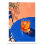 Orange cocktail with ice and an orange slice on a blue table, beside a blue chair and peach wall with leafy shadows.