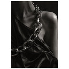 Oversized polished chain links cross dark, lustrous fabric beside a bare shoulder and neckline in black and white.