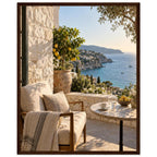 Lemon tree on a stone terrace with a cushioned chair, round table and blue sea overlooking a rocky coastline.