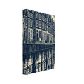 Gabled canal houses in navy and cream, with a street lamp, bicycles, an arched bridge and rippling reflections.