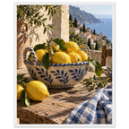 Lemons in a blue-and-white bowl on a wooden table, with olive branches, checked cloth and a coastal village beyond.