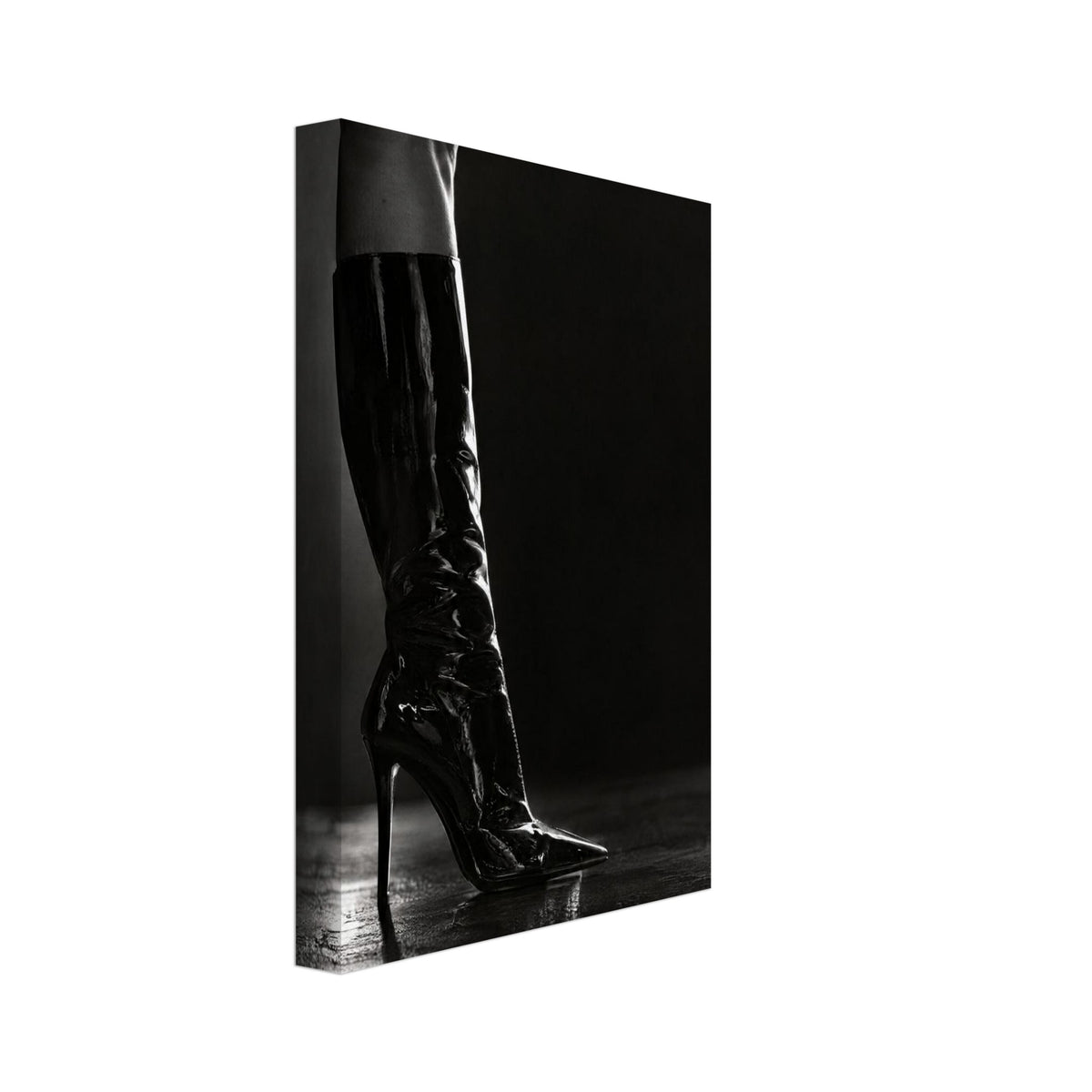 Black and white photograph of a leg in a glossy knee-high stiletto boot on a reflective floor against a dark backdrop.