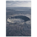 Large circular crater in a blue-grey desert plain, with rugged slopes, distant hills and a cloudy sky.