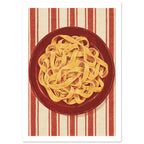 Golden pasta ribbons on a deep red plate, viewed from above against textured red and cream vertical stripes.