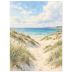 Sand dunes with grasses and footprints leading to turquoise waves beneath a blue sky with soft white clouds.