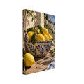 Lemons in a blue-and-cream ceramic bowl on a rustic table, with olive branches, checked cloth and a coastal view.