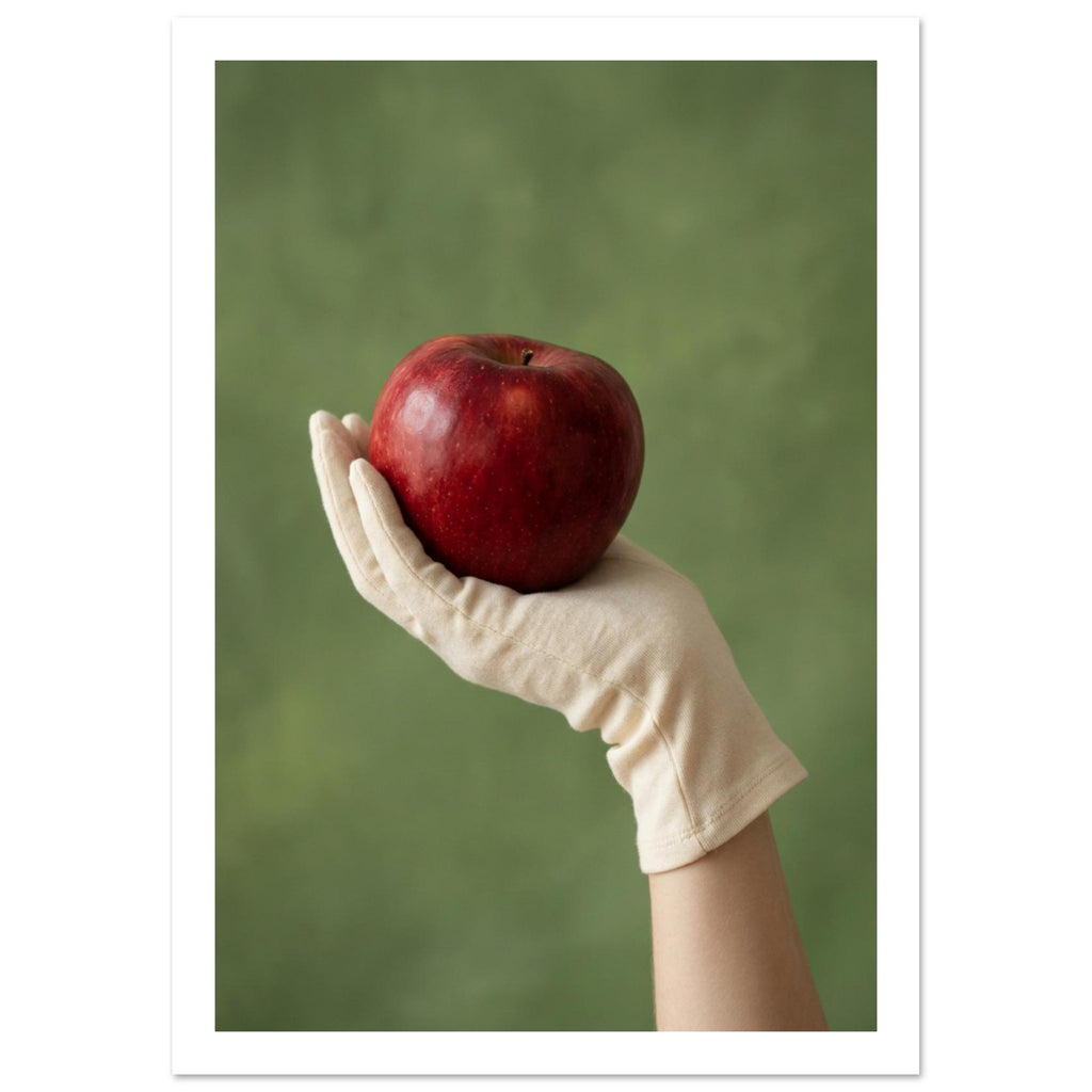 Red apple resting in a cream-gloved hand, with a bare forearm below and a softly blurred green background.