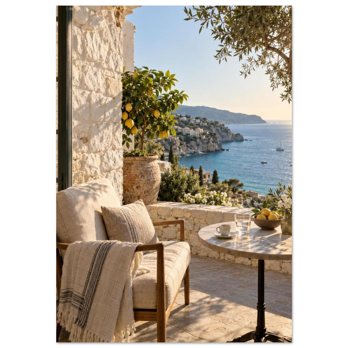 Lemon tree on a stone terrace with a cushioned chair, round table and blue sea overlooking a rocky coastline.