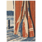 Four weathered red, blue and cream wooden oars leaning against red timber boards beside water and a wooden jetty.