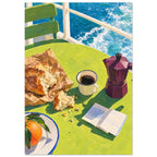Seaside breakfast with bread, coffee, a plum moka pot, an orange and an open book on a green table beside blue water.