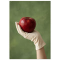 Red apple resting in a cream-gloved hand, with a bare forearm below and a softly blurred green background.