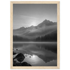 Mountain peaks and conifer forests reflected in a misty lake, with rocks in the foreground, in black and white.