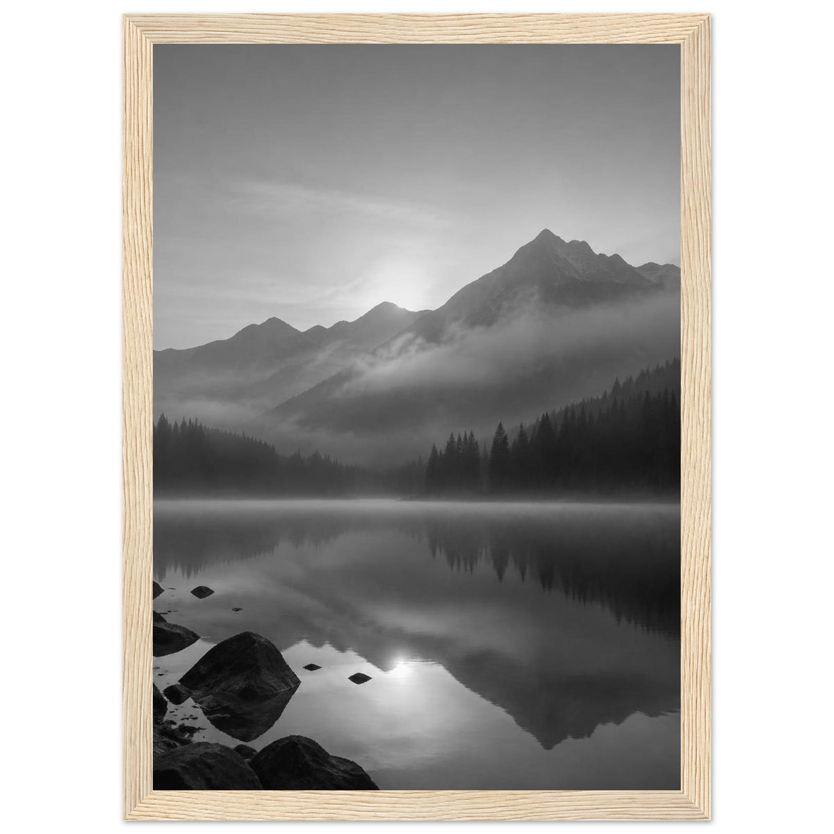Mountain peaks and conifer forests reflected in a misty lake, with rocks in the foreground, in black and white.
