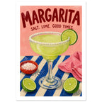 Margarita glass with salted rim, limes and salt bowl on a blue striped table beneath red lettering on pink.