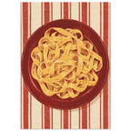 Golden pasta ribbons on a deep red plate, viewed from above against textured red and cream vertical stripes.