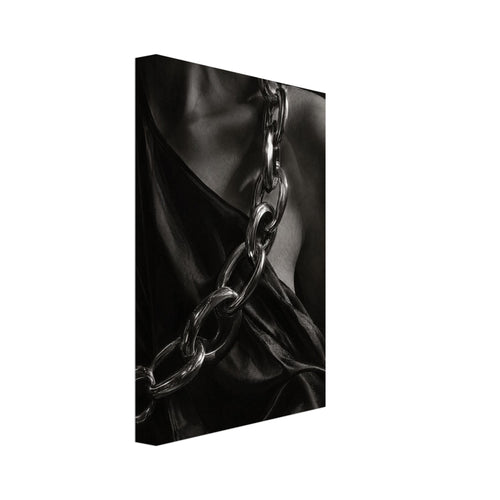 Oversized polished chain links cross dark, lustrous fabric beside a bare shoulder and neckline in black and white.