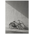 Bicycle leaning against a textured wall, with diagonal sunlight and long shadows across the wall and pavement.