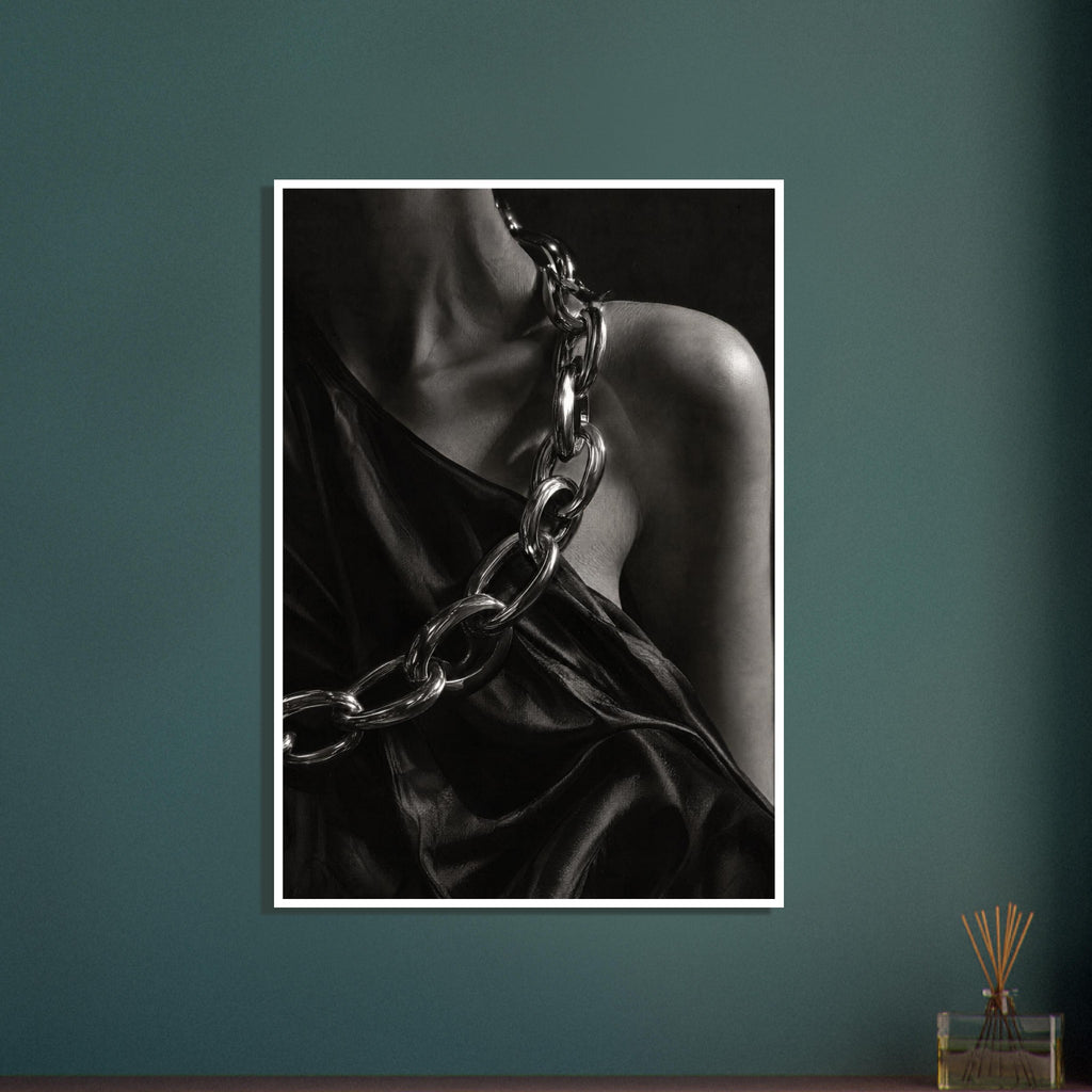 Oversized polished chain links cross dark, lustrous fabric beside a bare shoulder and neckline in black and white.