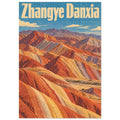 Striped orange, yellow and grey mountain ridges beneath a blue sky, with large cream Zhangye Danxia lettering.