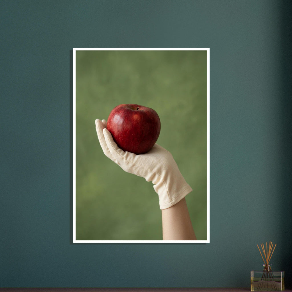 Red apple resting in a cream-gloved hand, with a bare forearm below and a softly blurred green background.