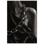Oversized polished chain links cross dark, lustrous fabric beside a bare shoulder and neckline in black and white.