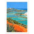 Coastal salt pans with turquoise pools, orange earth, green plants, a white salt mound and a distant village under blue sky.