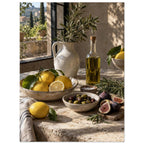 Lemons, olives, figs and a bottle of oil on a stone table beside a ceramic jug of leafy branches and a sunlit window.