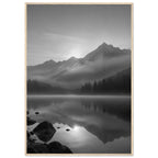 Mountain peaks and conifer forests reflected in a misty lake, with rocks in the foreground, in black and white.